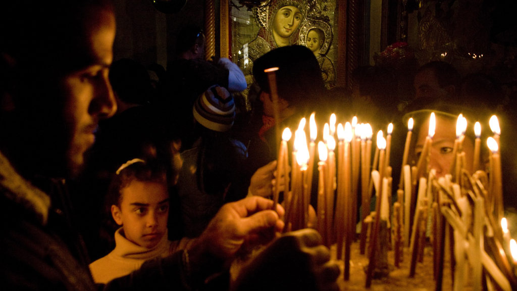 Worshippers light candles in the Church of the Nativity.