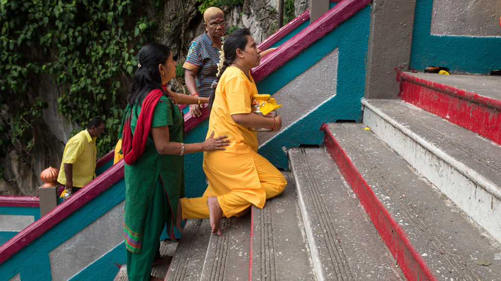 A woman climps the steps to the Batu Caves on her knees. 