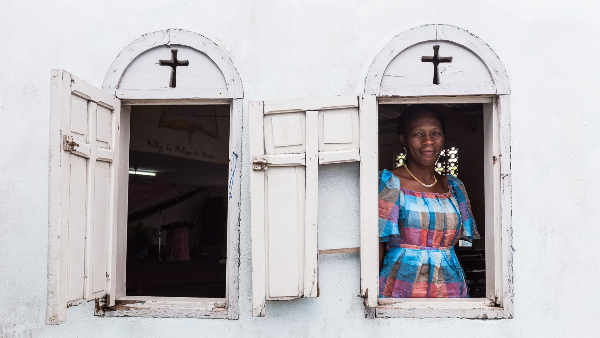 a woman looks out of a window in a church in Ivory Coast