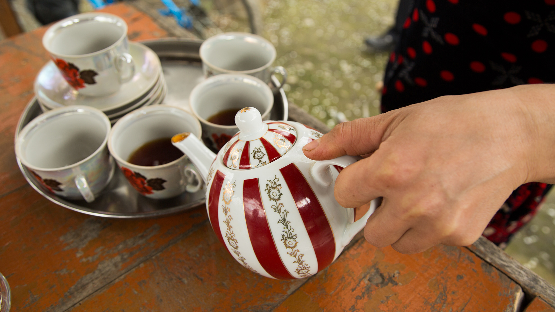 A Central Asian woman pours tea for guests