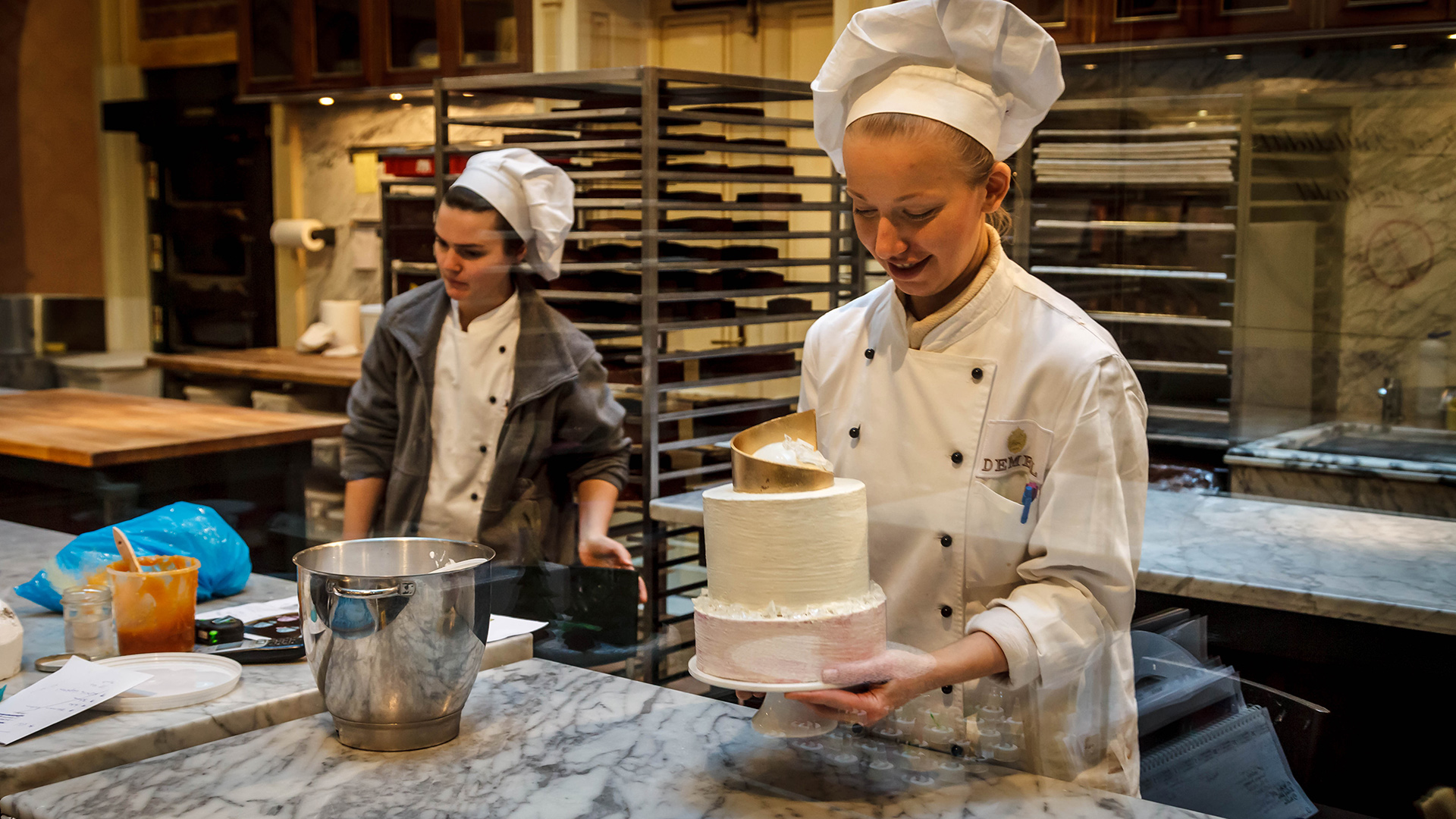 A chef takes pride in her work as she decorates a cake.