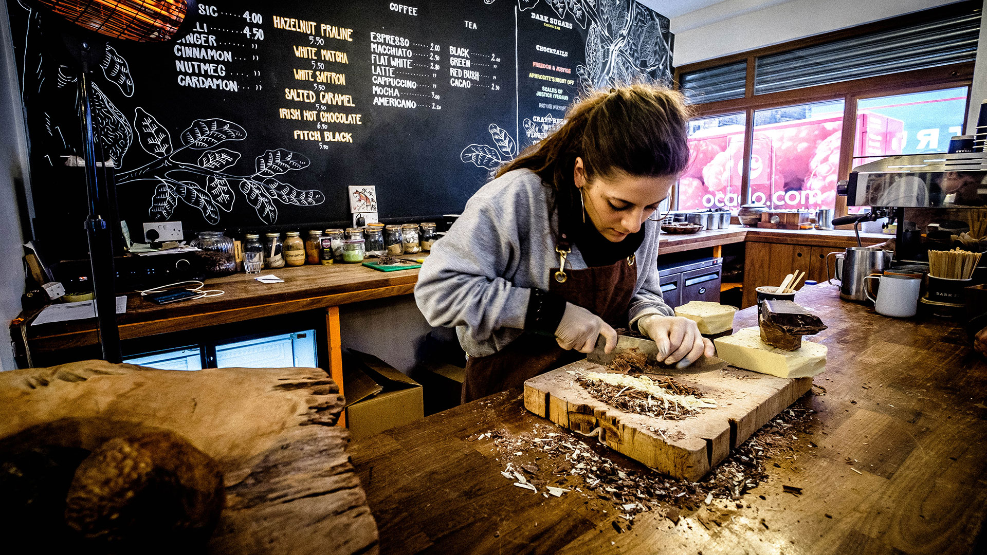 A woman shaves chocolate curls for a fancy cup of coffee in one of London's many boutique coffee shops. 