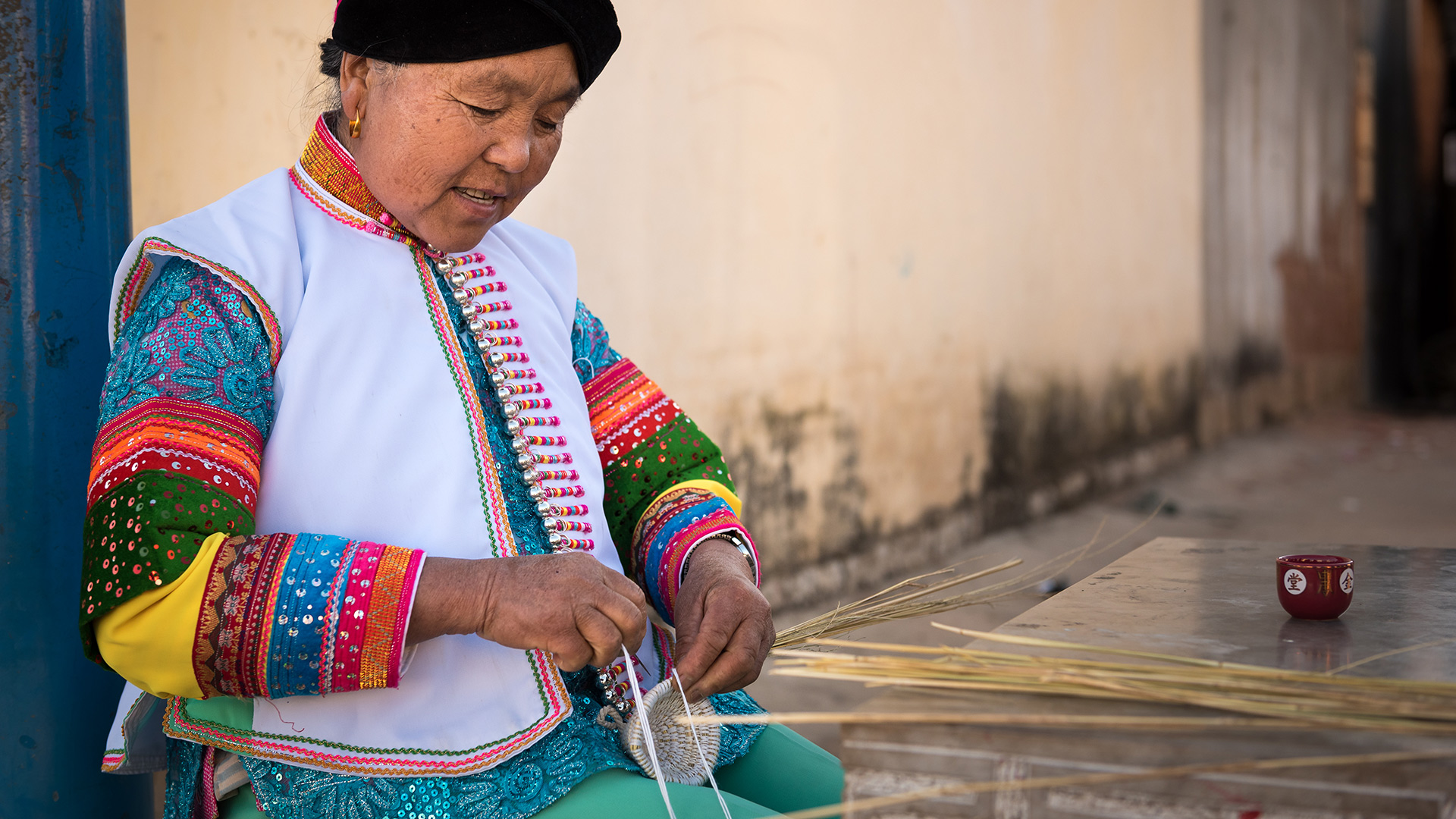 A Mongol woman makes a traditional woven handicraft using a cotton string and straw.