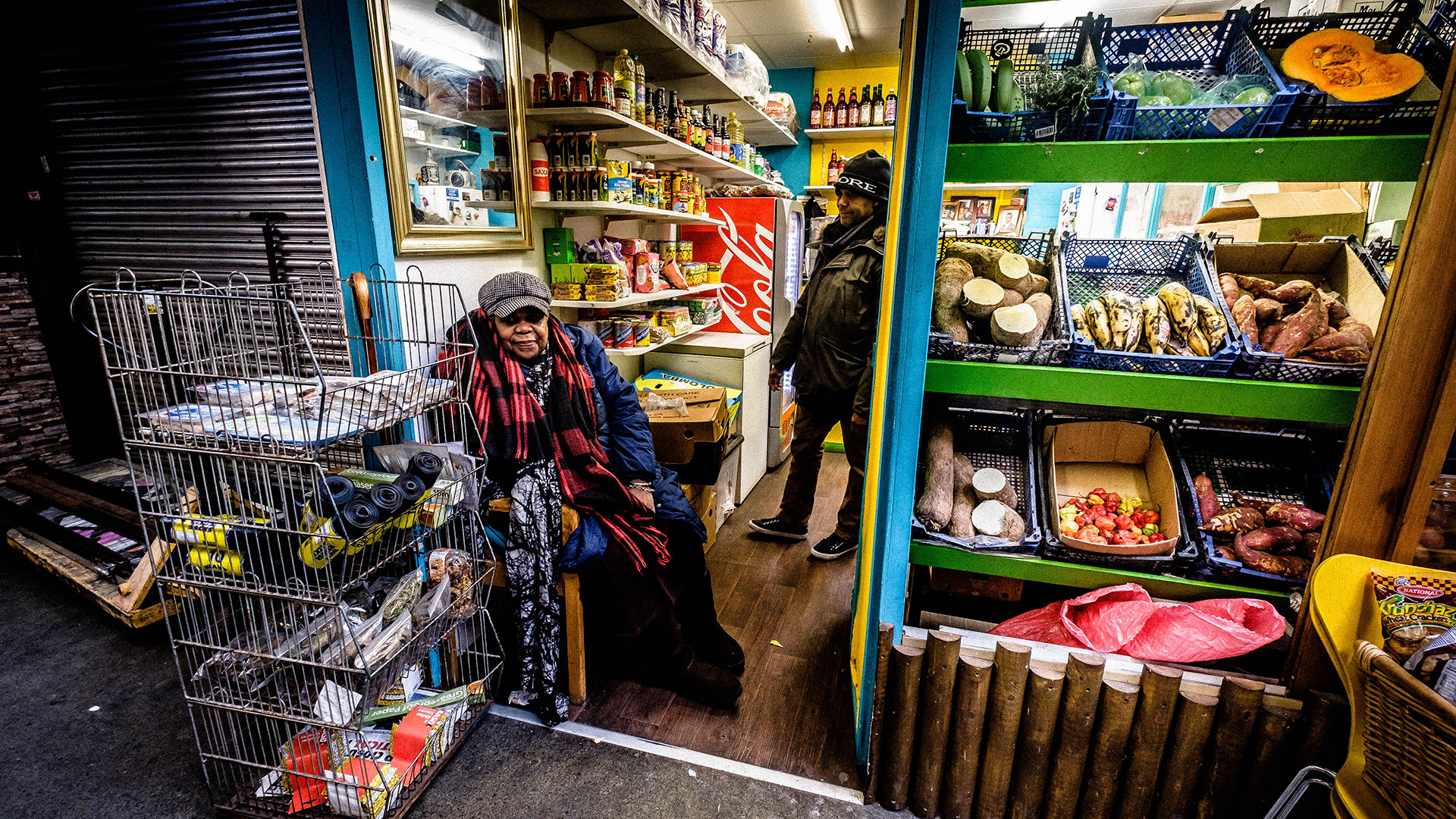 A Jamaican shopkeeper sits in front of her grocery store in London. 