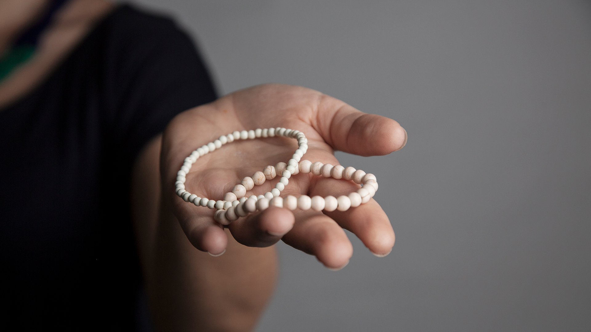 A woman offers two ivory bracelets as a gift.