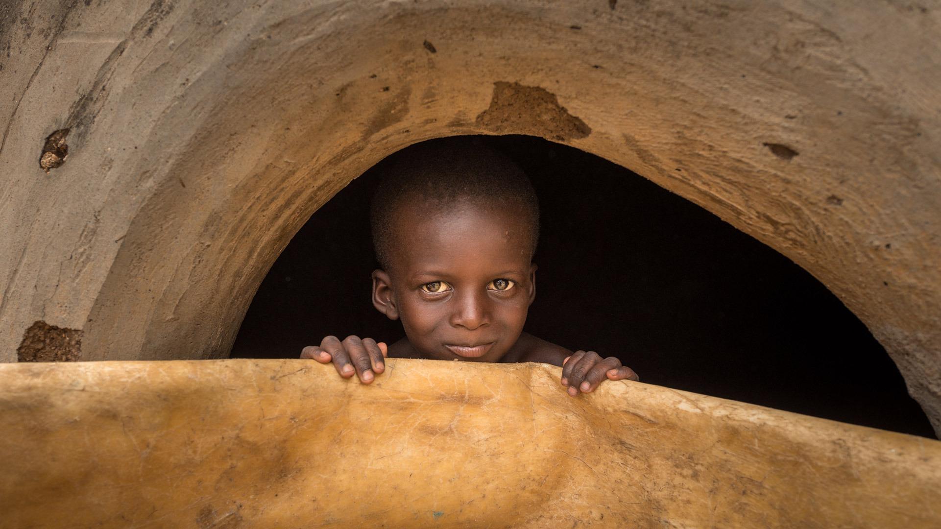 A Talensi boy peers out from inside a shrine.