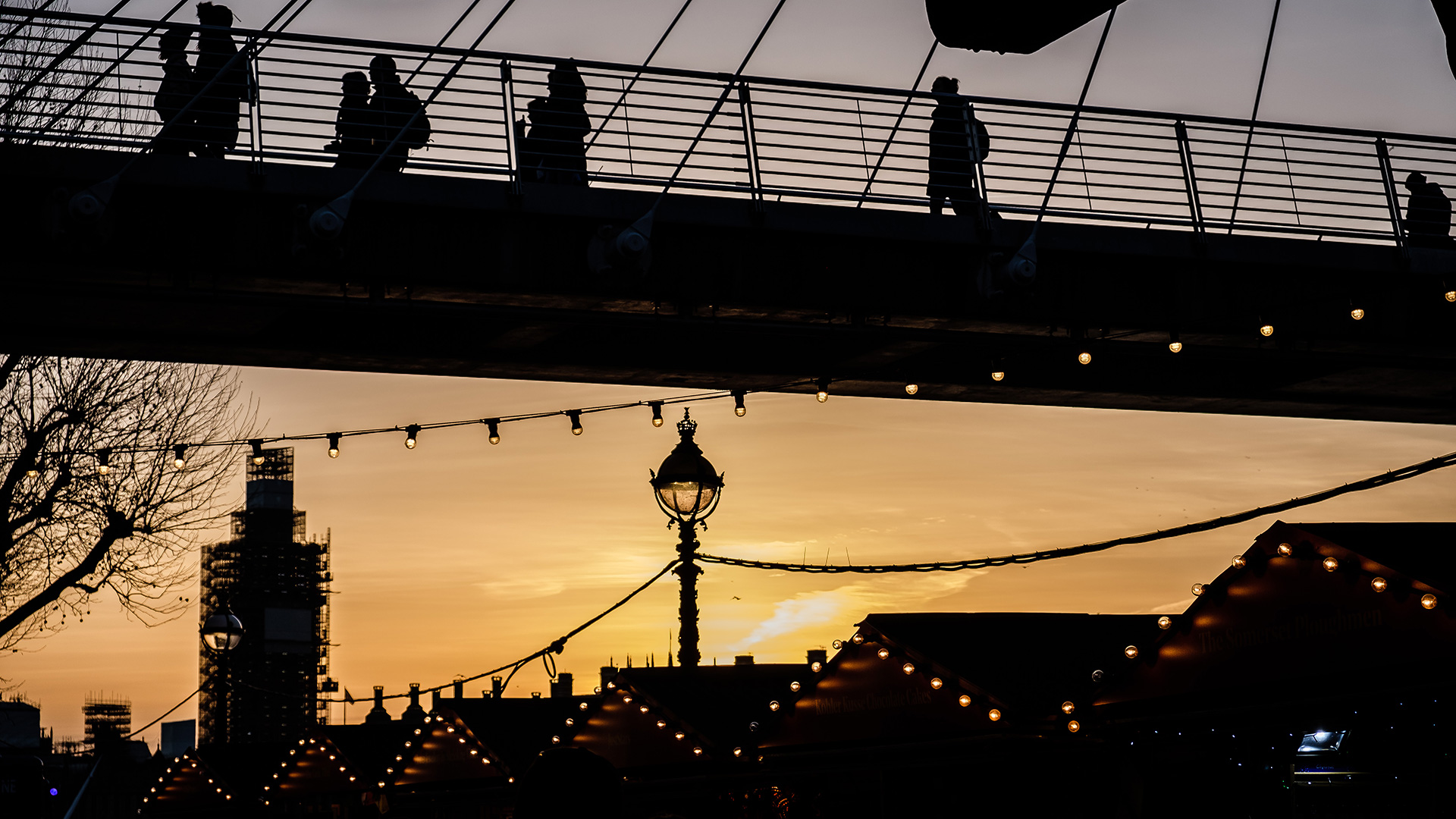 The sun sets over one of London's Christmas markets as commuters head home over Hungerford Bridge.
